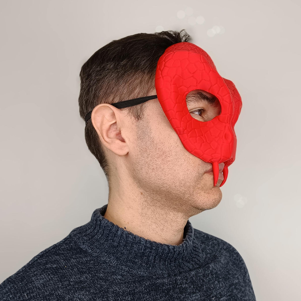 Side view of a man wearing a 3D printed red snake demon mask with reptilian texture for cosplay.