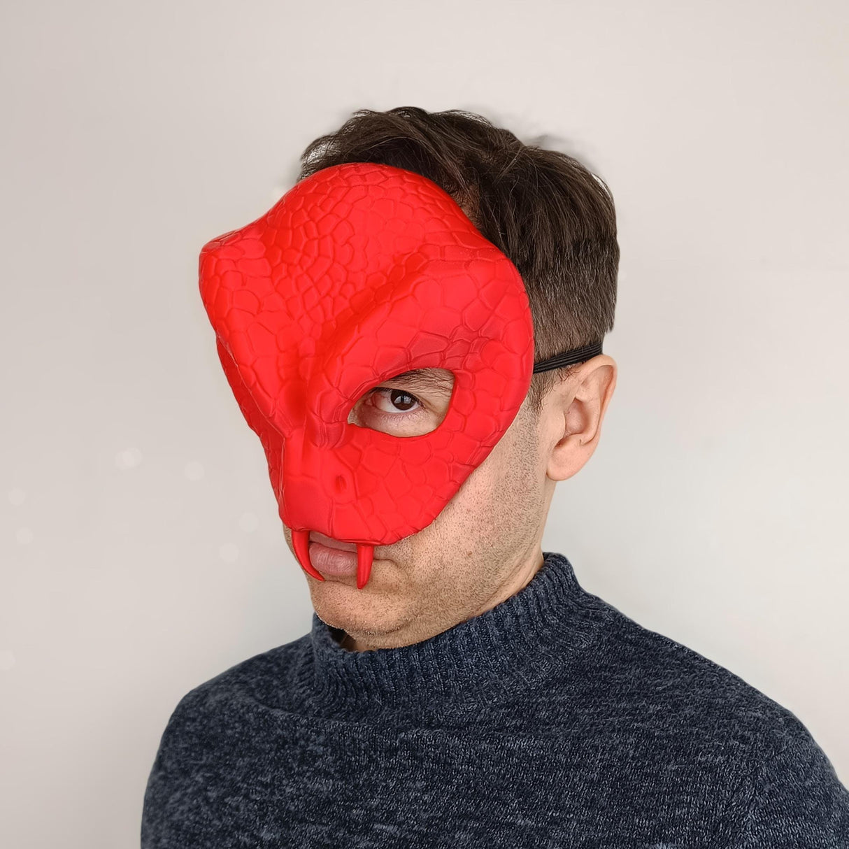 Man wearing a red 3D printed snake demon mask with realistic scale texture for cosplay or Halloween.
