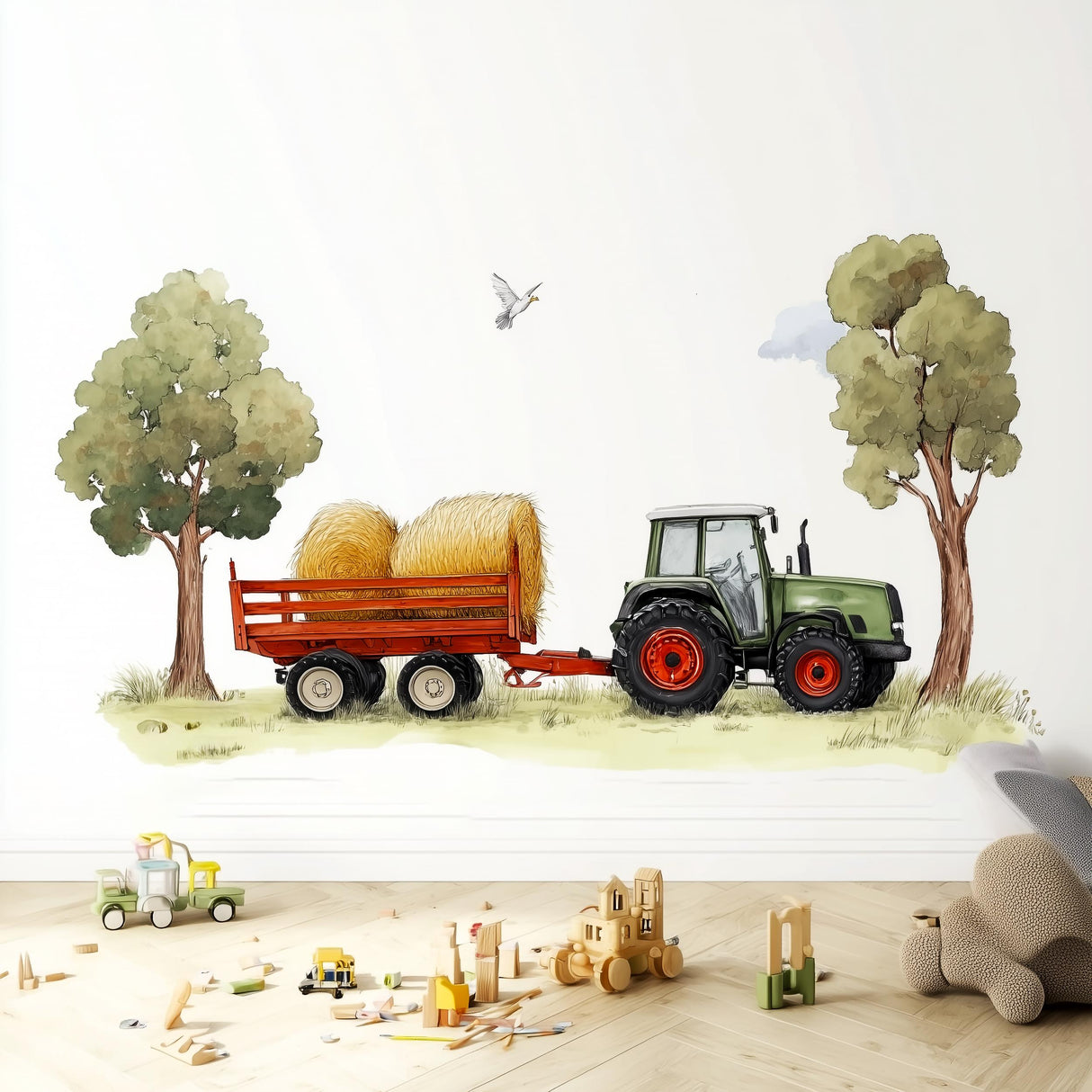 A playful wall decal featuring a green farm tractor pulling a trailer with hay bales between two trees, placed in a child's room above a wooden floor with toy blocks and trucks scattered around.