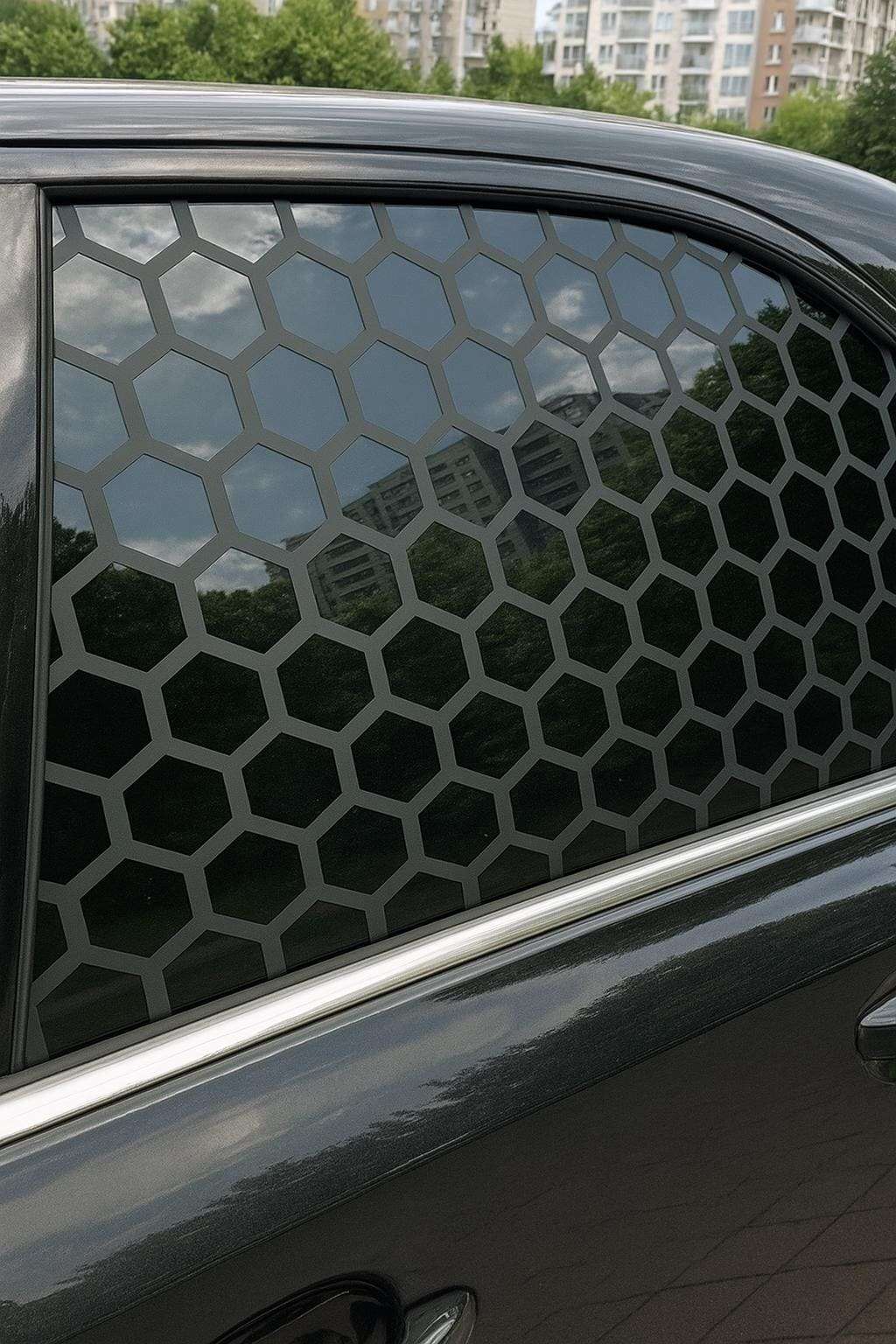 Black car window with matte black honeycomb vinyl decal applied; geometric hexagonal pattern overlaying tinted glass in a sleek, symmetrical design.