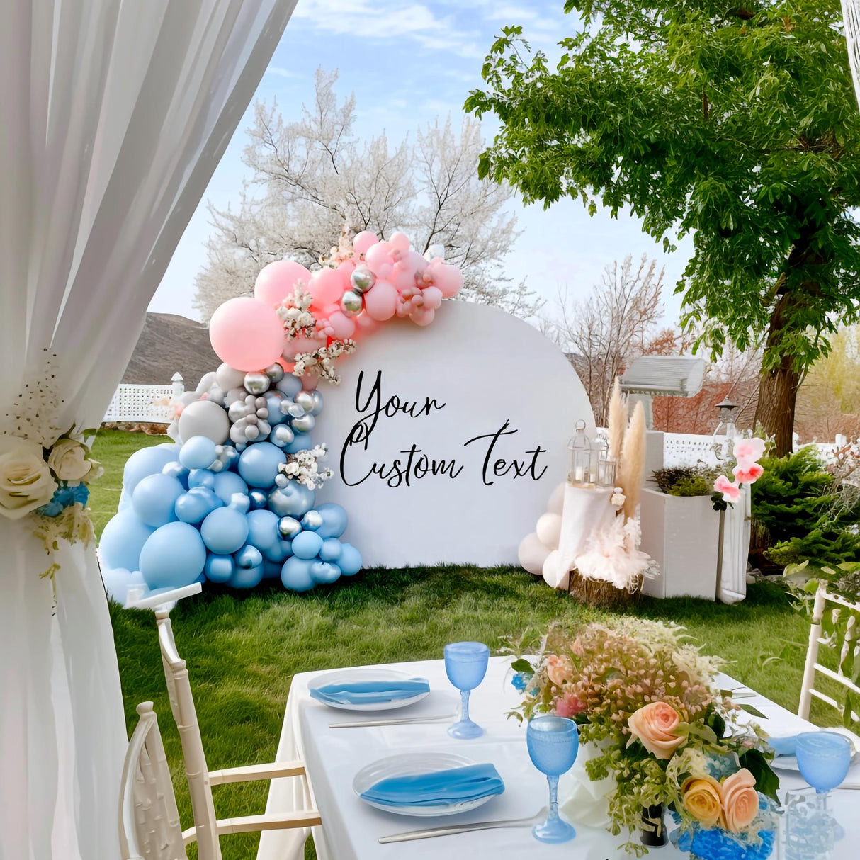 Outdoor wedding setup featuring a pastel balloon arch in pink, silver, and blue, arranged around a white backdrop arch with custom black vinyl text reading “Your Custom Text” in a romantic script style.