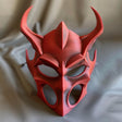 3D printed demon mask with horned gothic design made of matte PLA plastic, displayed on fabric background, dark fantasy cosplay and Halloween art accessory