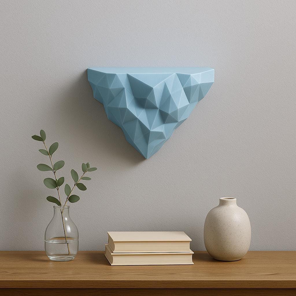 Geometric 3D printed blue wall shelf with a polygonal faceted design, mounted above a wooden console table with books, a ceramic vase, and glass bud vase.