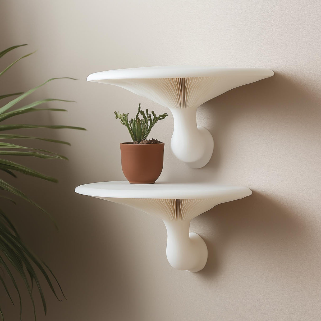 "Pair of white 3D printed mushroom-inspired wall shelves mounted on a neutral wall, styled with a terracotta potted cactus."