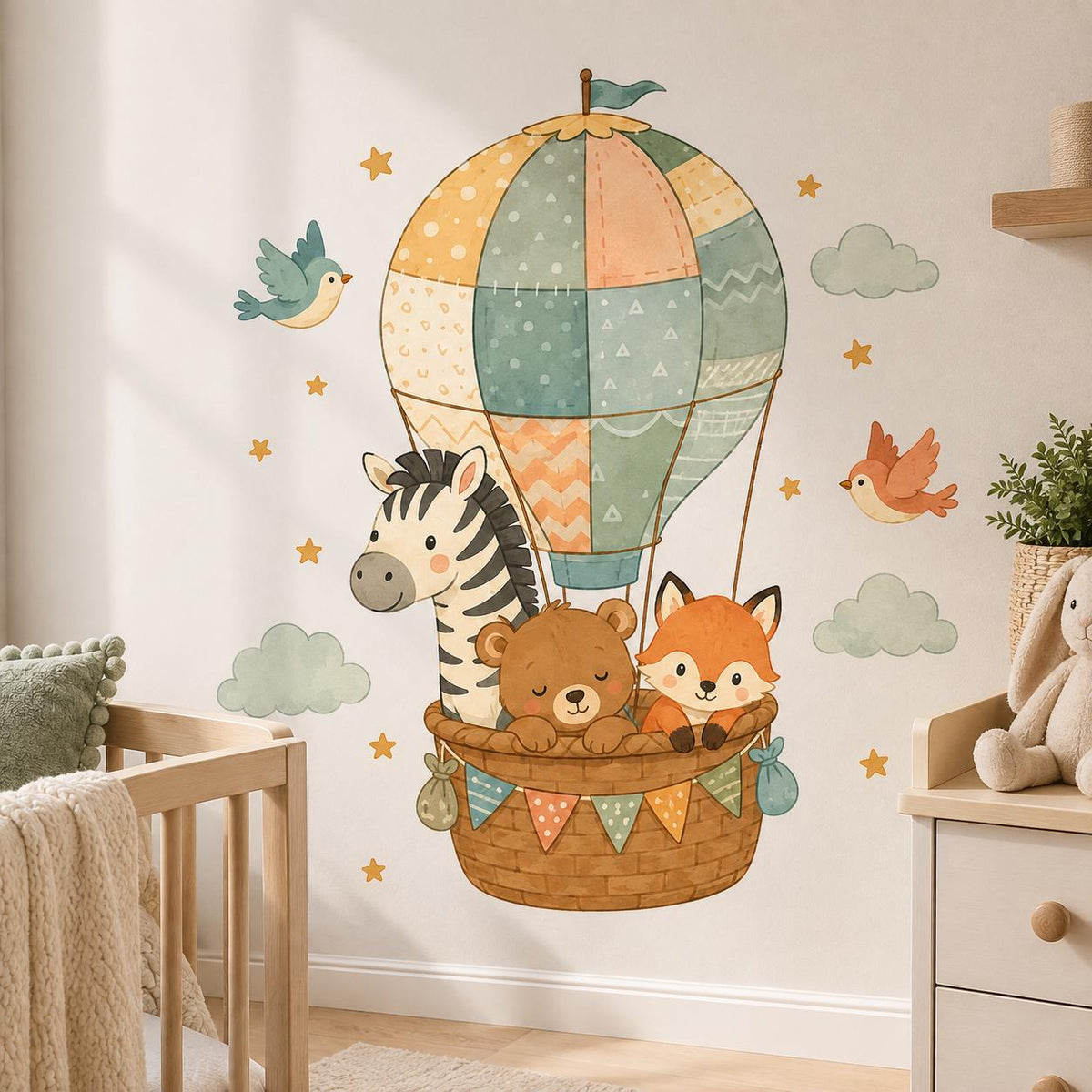 Patchwork hot air balloon wall decal carrying a zebra, sleeping bear and fox, with birds, pale green clouds and golden stars.