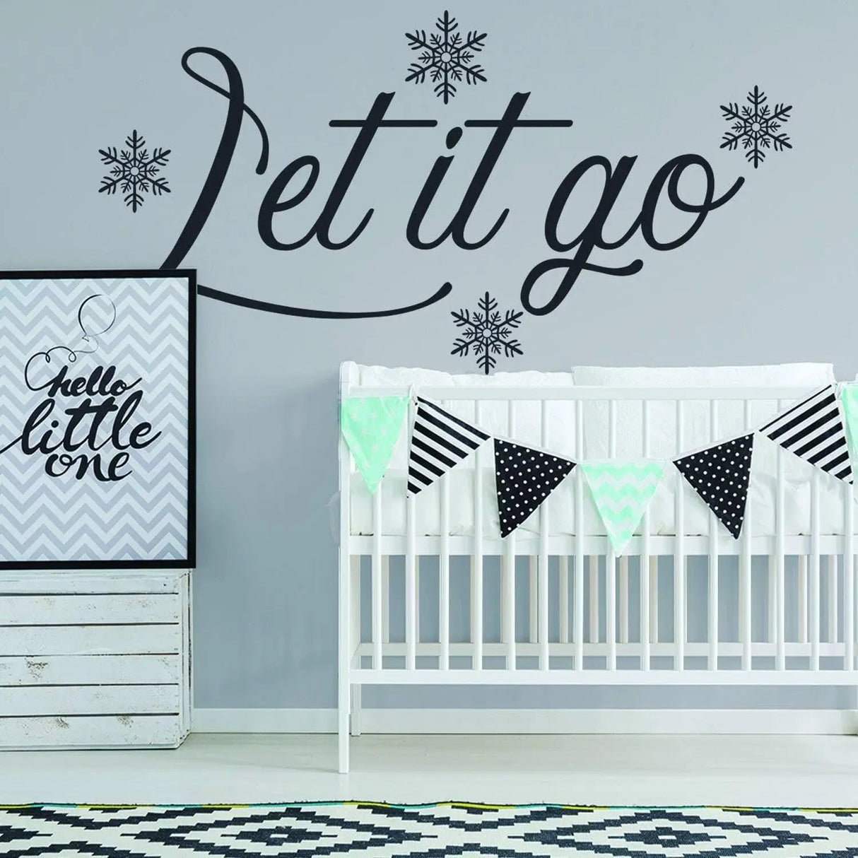 Inspirational wall sticker with 'Let it go' text and snowflakes above a crib in a cozy nursery.