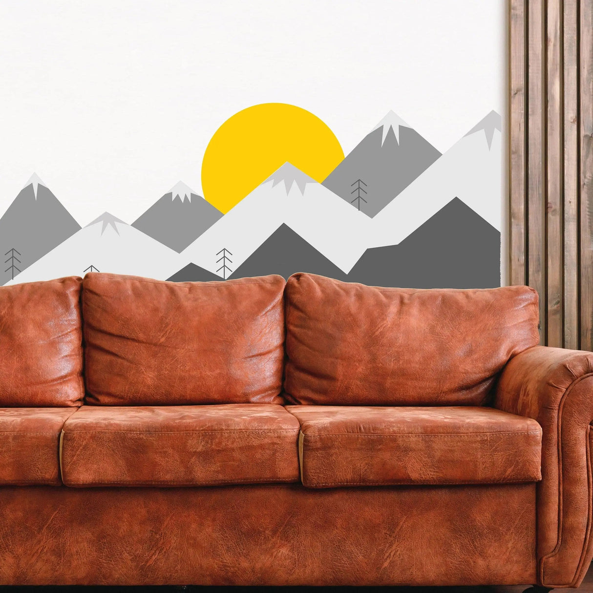 Majestic mountain wall decal featuring a yellow sun, enhancing interior design above a brown couch.