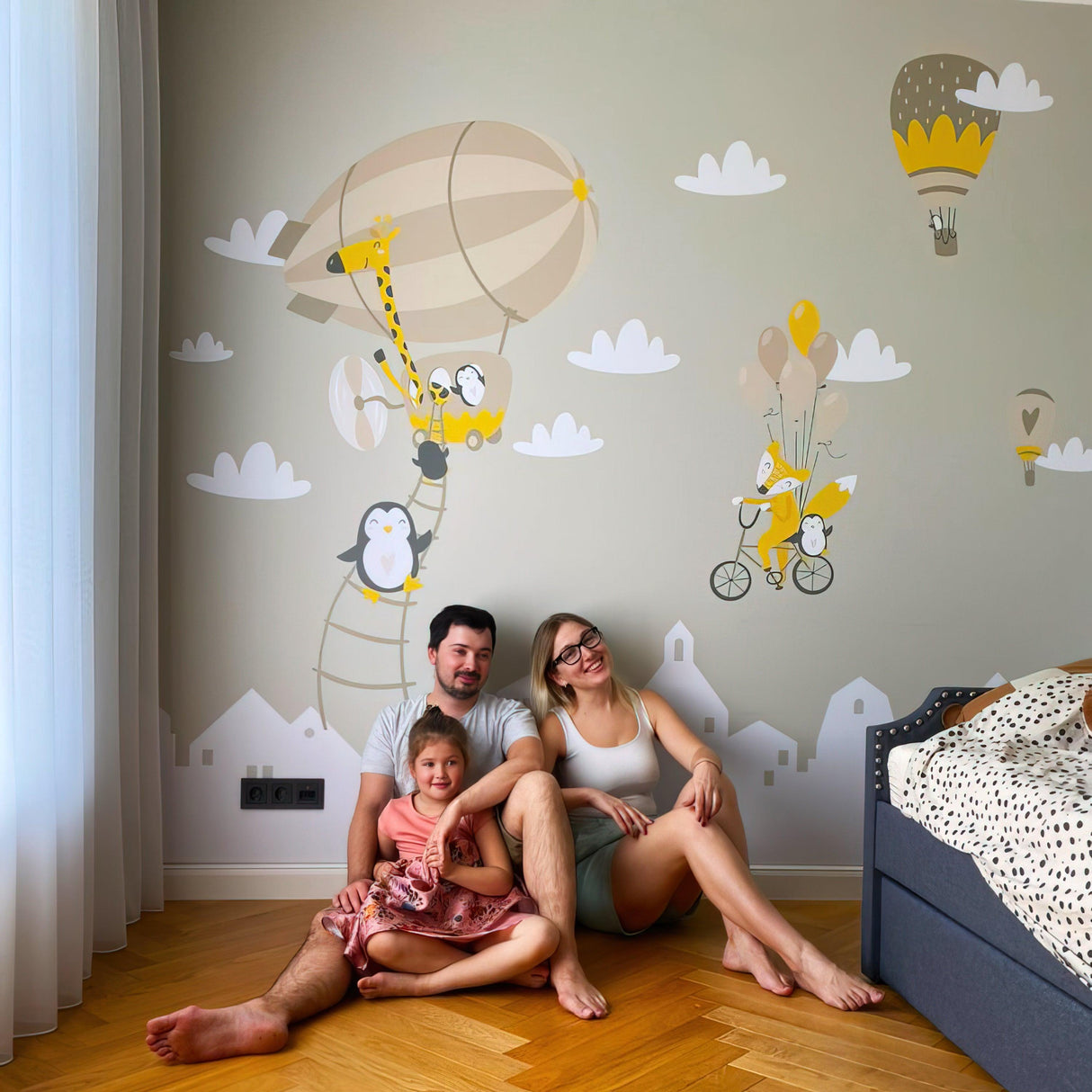 Family enjoying whimsical wall decals featuring penguins, foxes, and hot air balloons in a nursery.