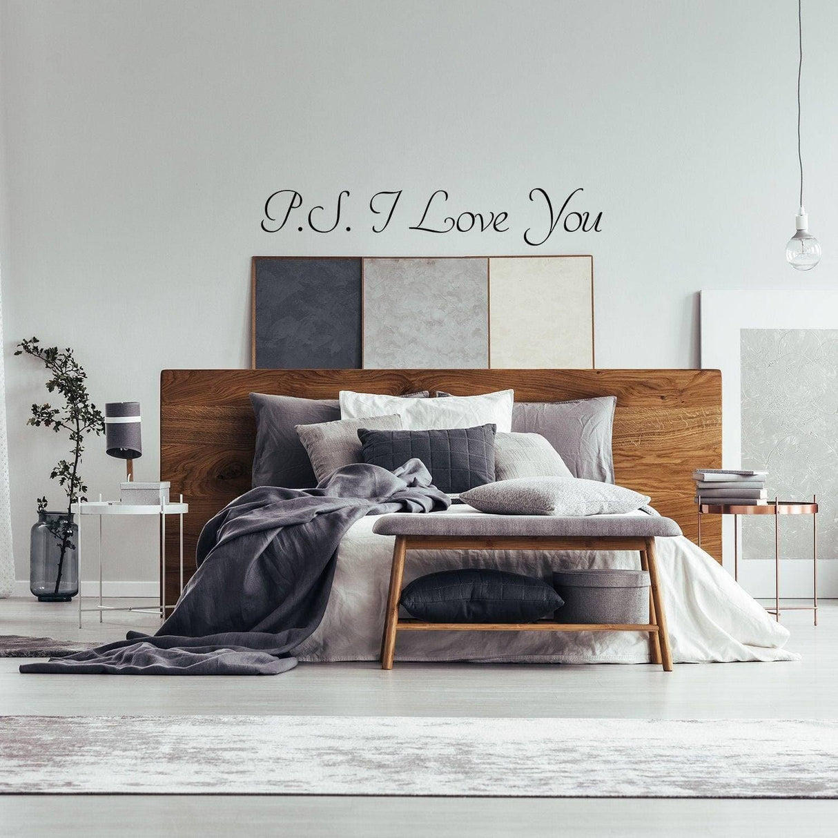 Romantic bedroom featuring a 'P.S. I Love You' wall decal above a cozy bed with gray bedding and stylish decor.