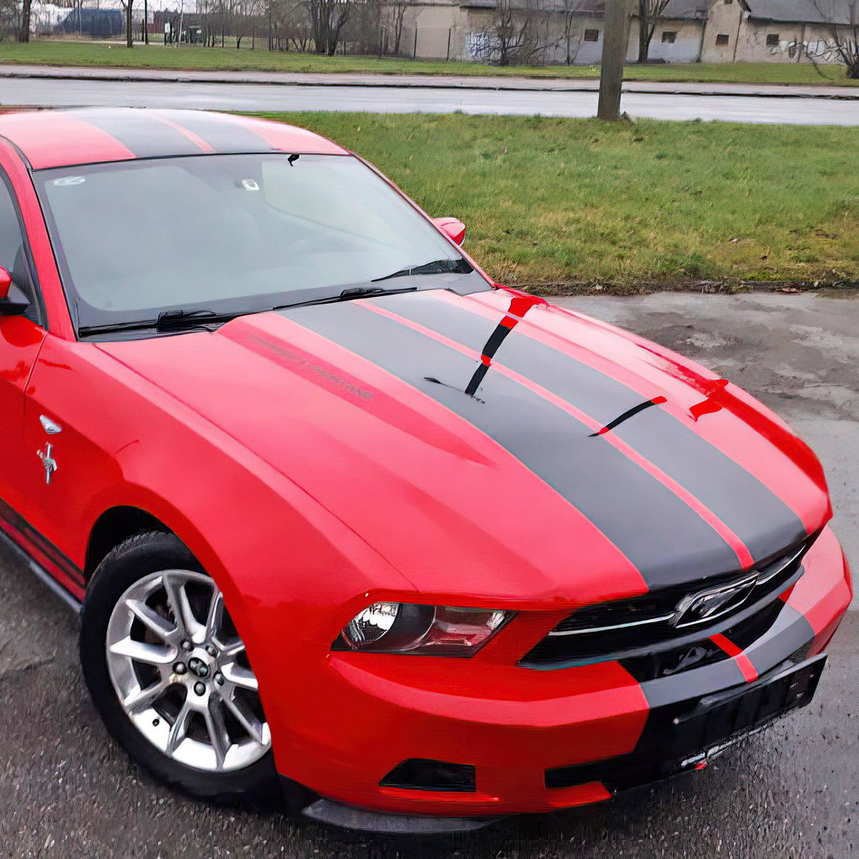 Red car with black racing stripes vinyl decal, showcasing a sporty look and sleek design on the highway.