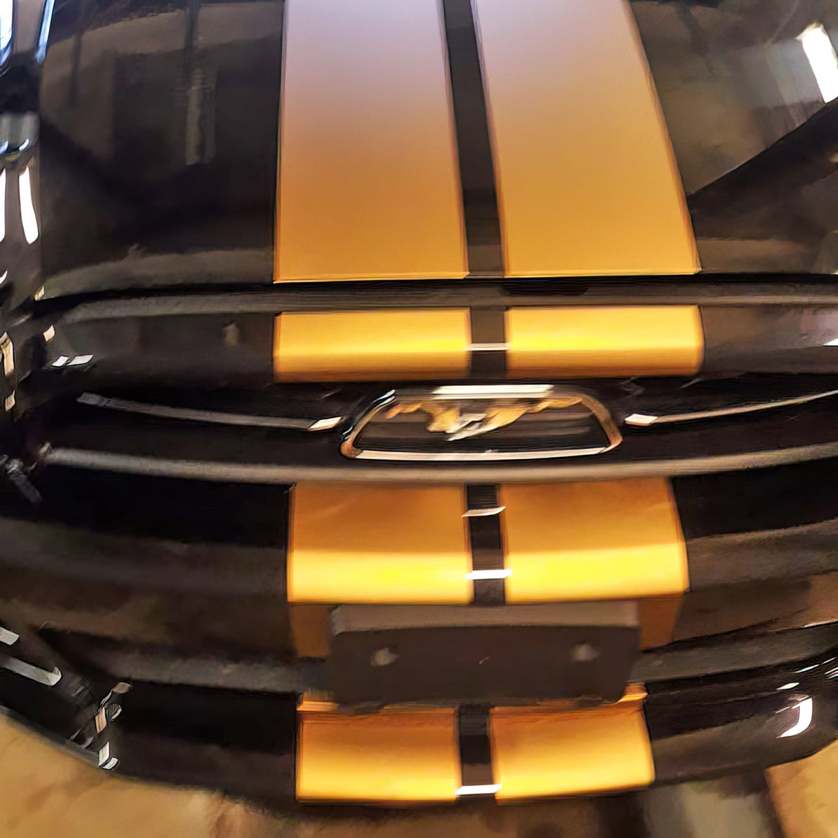 Black car with yellow racing stripes on the hood, showcasing sporty vinyl decals for a stylish upgrade.
