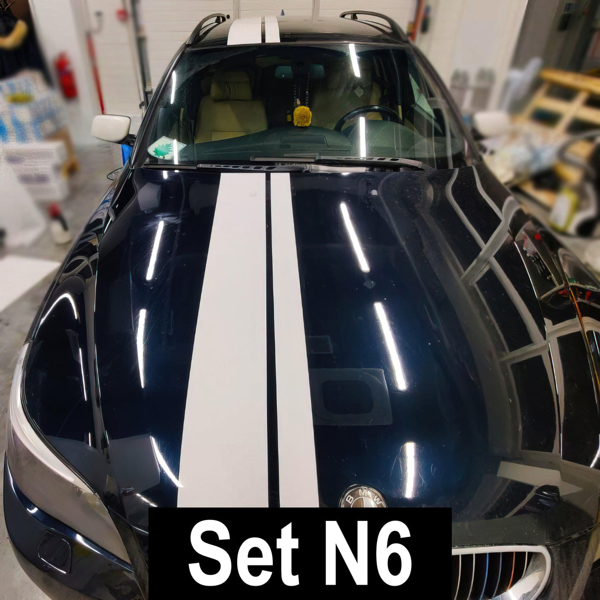 Car with white racing stripes vinyl decals on a dark blue vehicle, showcasing sporty vehicle graphics.