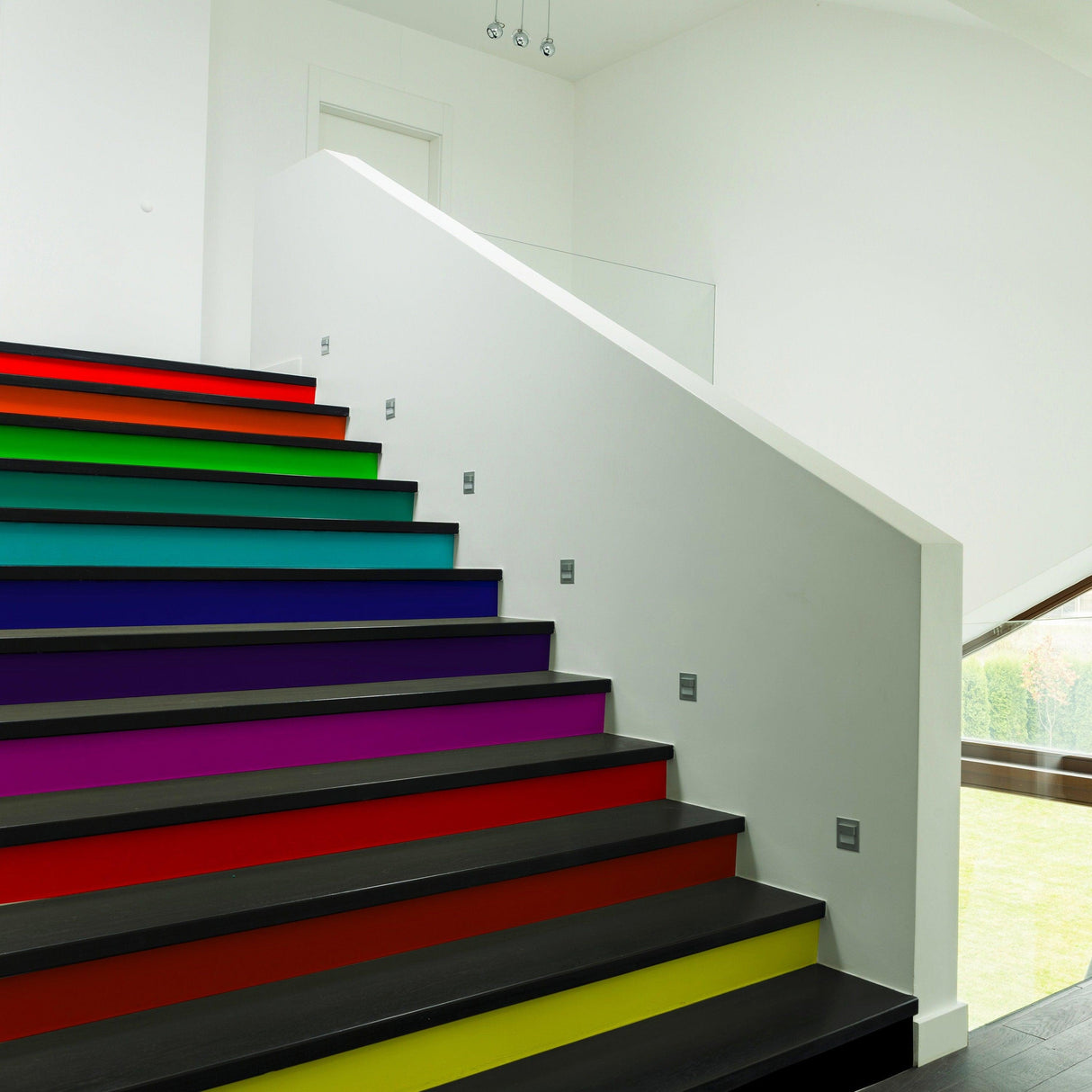 Colorful rainbow stair riser decals transforming a modern staircase with vibrant hues.
