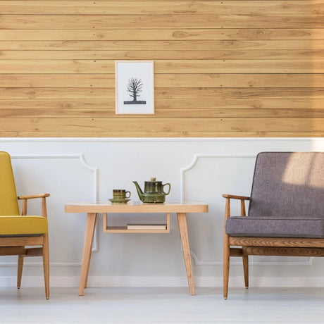Cozy living room with rustic wood wallpaper, yellow and gray chairs, and a wooden table with teapot and cups.