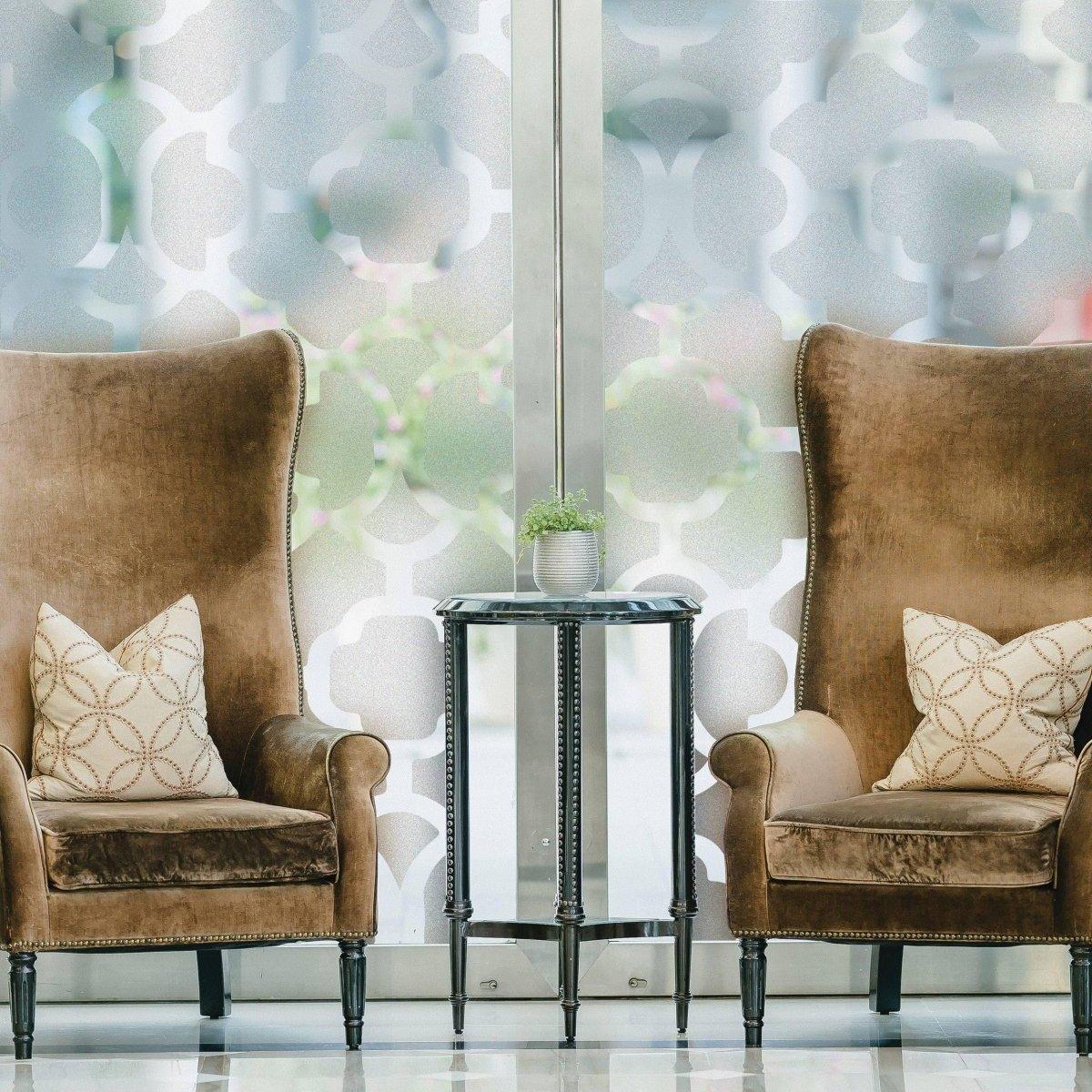 Stylish privacy glass window film decorates a bright space featuring two cozy armchairs and a small side table.