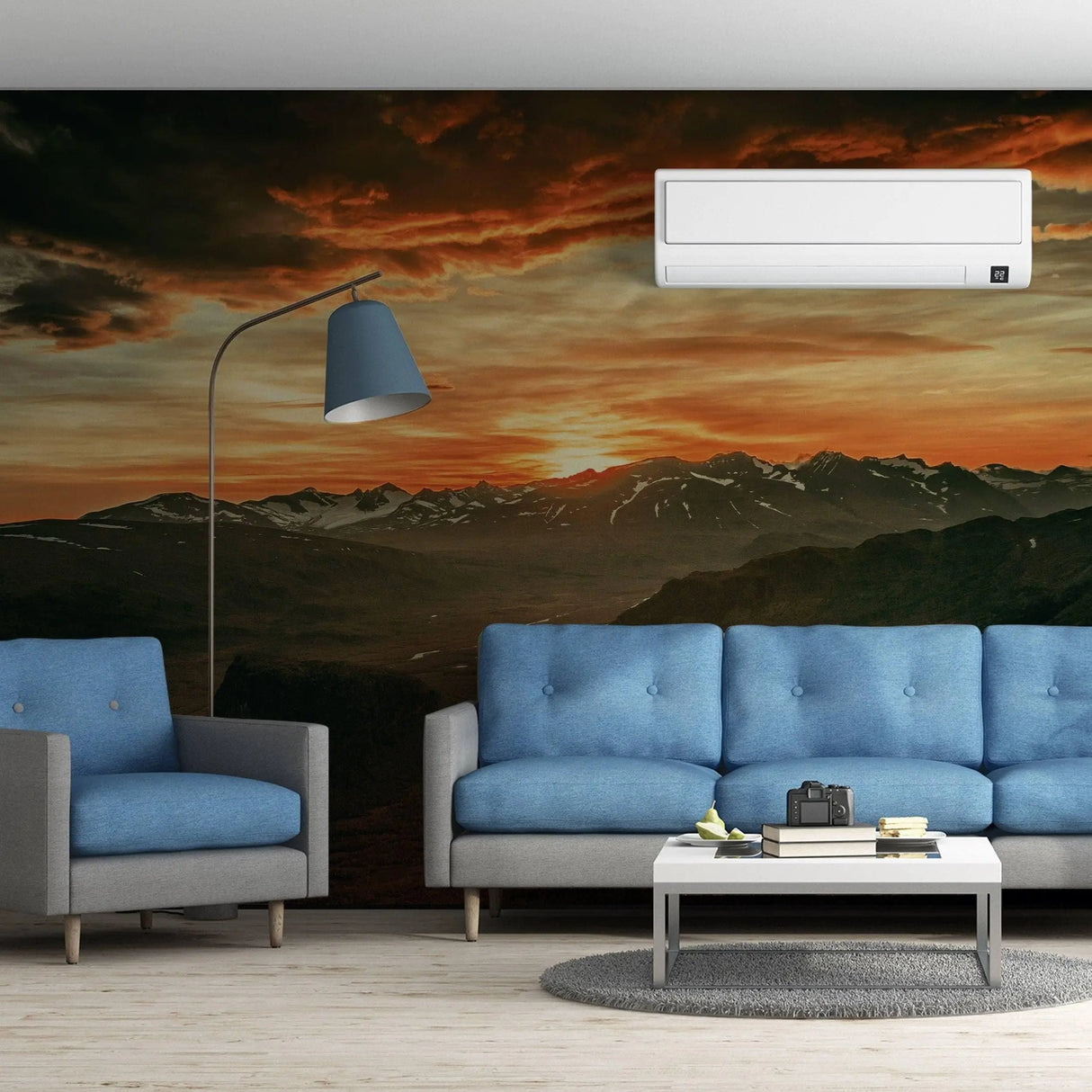 Cozy living room featuring a majestic sunset wall sticker, blue sofas, and warm mountain scenery.