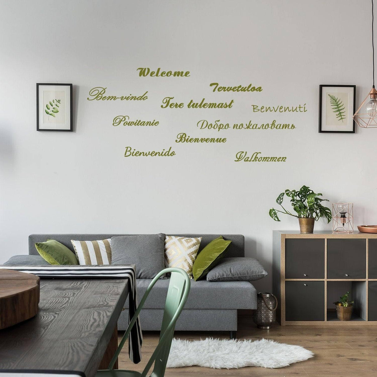 Stylish wall decal with 'Welcome' in multiple languages above a modern living room sofa and decor.