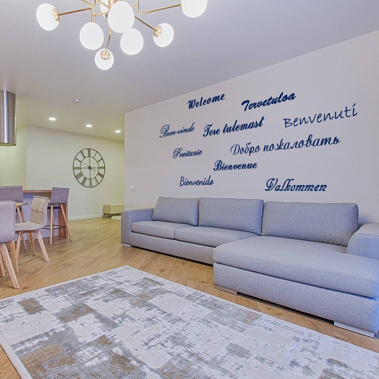 Modern living room with welcoming wall decals in multiple languages, featuring a cozy sofa and stylish decor.