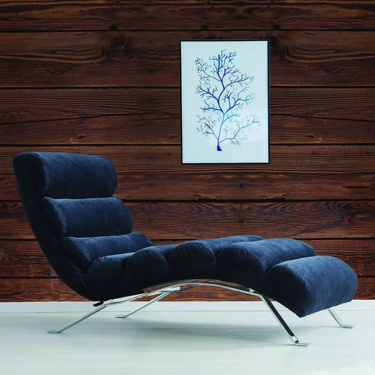 Stylish blue lounge chair next to a framed art piece on a rustic wood wall, showcasing a cozy living space.