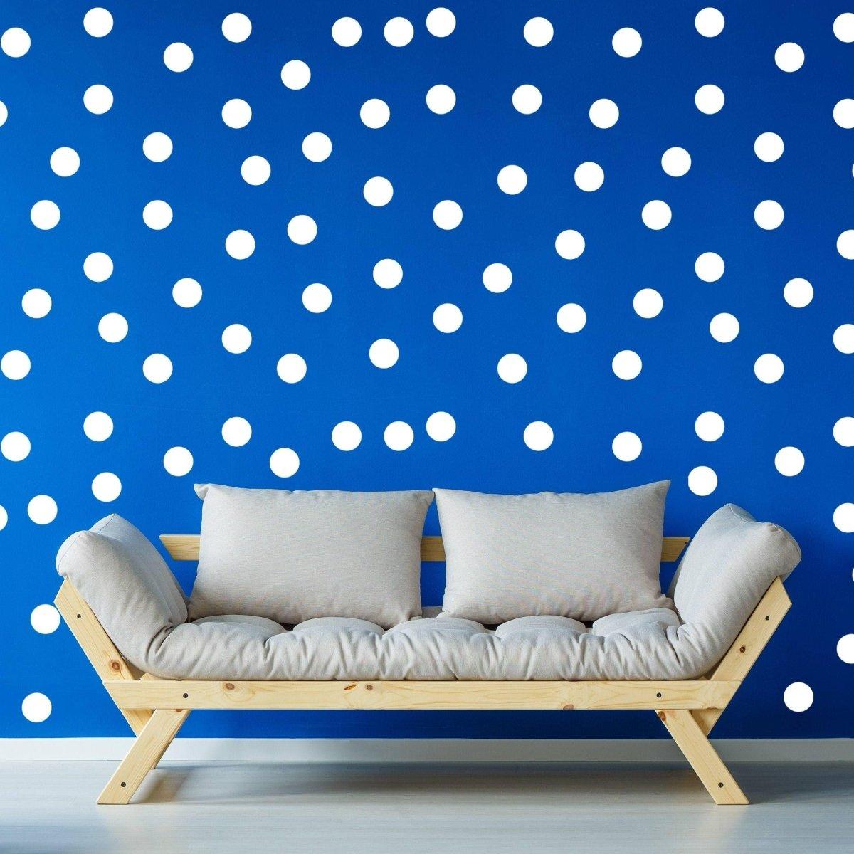 Colorful 2-inch round dot wall stickers on a blue wall behind a modern wood sofa, adding vibrant decor.