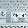 Stylish nursery featuring geometric triangle wall decals, a crib, and decorative bunting for a charming kids' room.