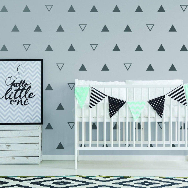 Stylish nursery featuring geometric triangle wall decals, a crib, and decorative bunting for a charming kids' room.