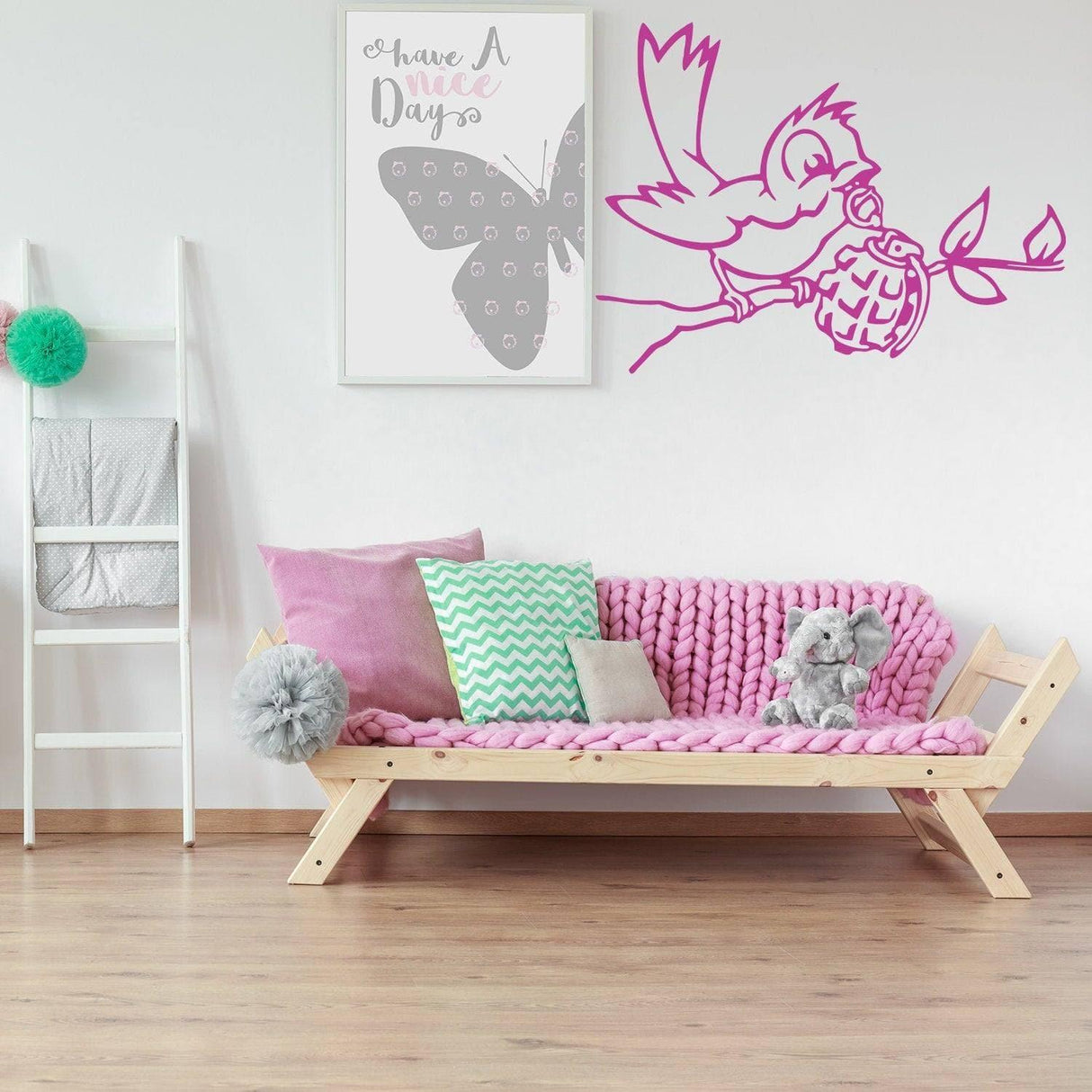 Banksy bird wall decal in pink on white wall above cozy pink sofa in stylish room decor.