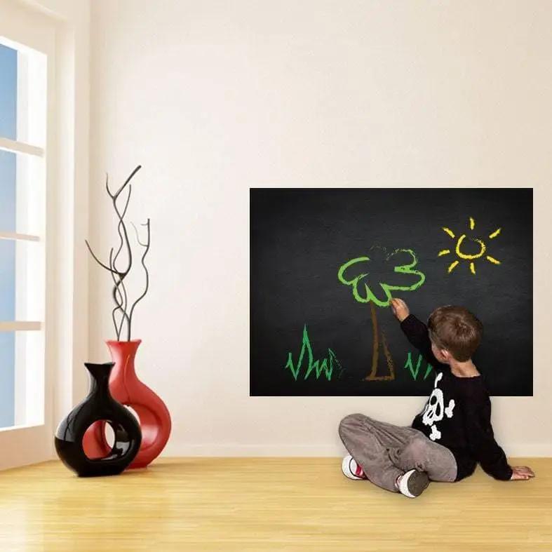 Child drawing on a reusable chalkboard wall sticker featuring a tree and sun in a colorful living room.