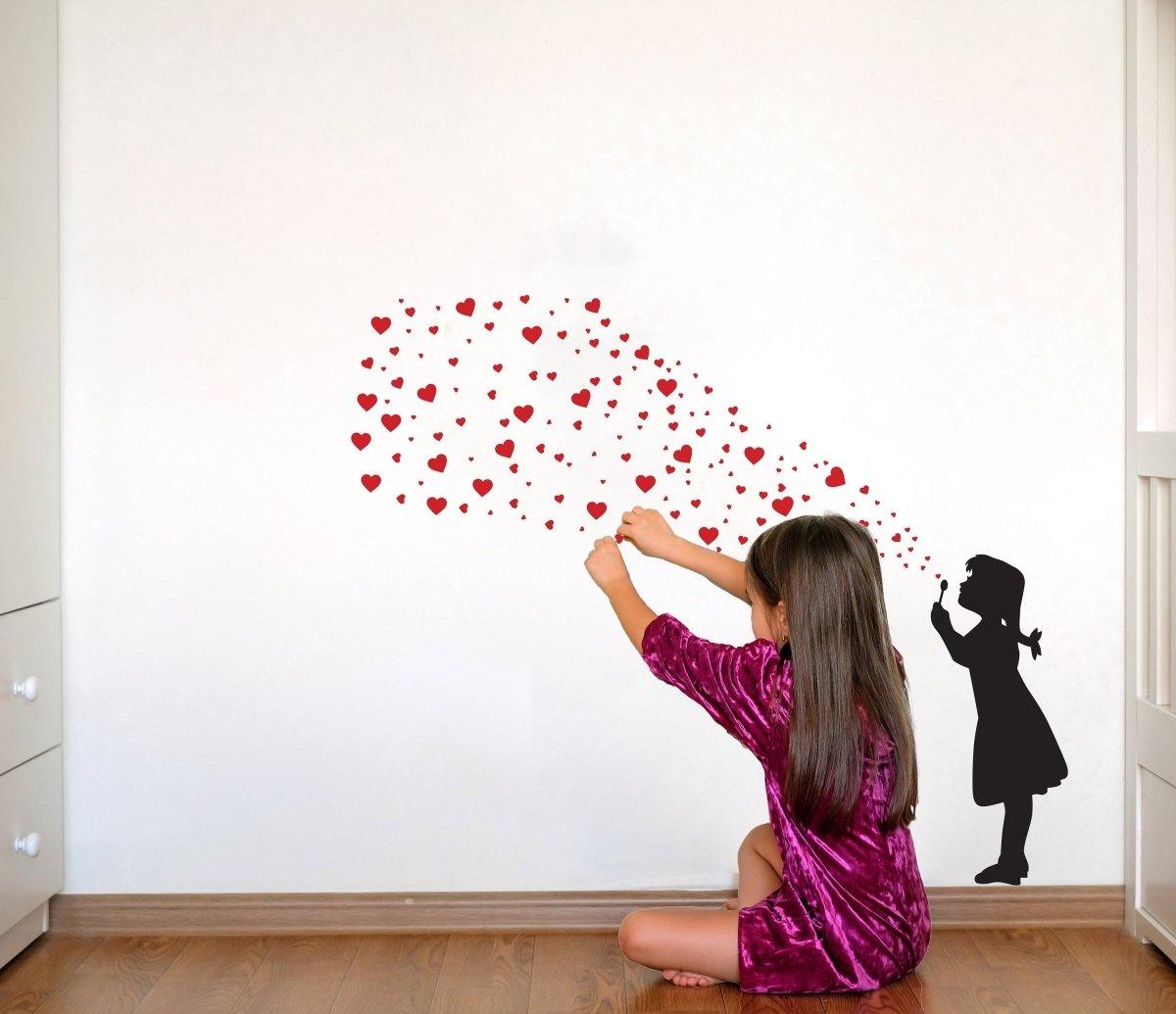 Girl applying heart bubble wall decal in a stylish room, showcasing playful street art design.