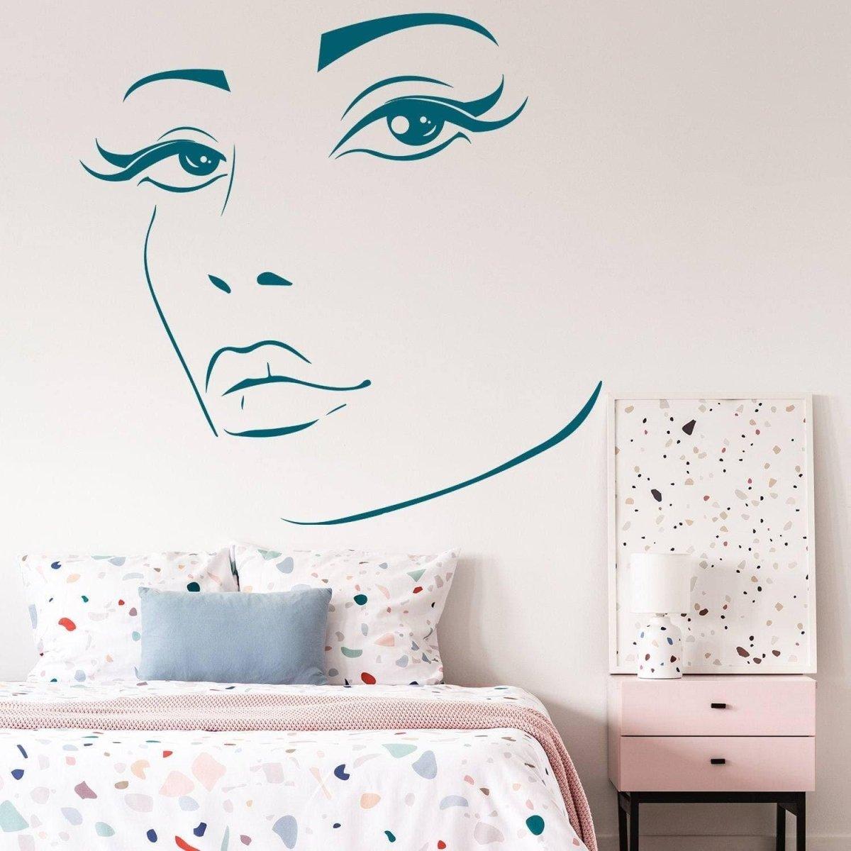 Charming woman face vinyl wall decal above a colorful bed, perfect for modern interior design.