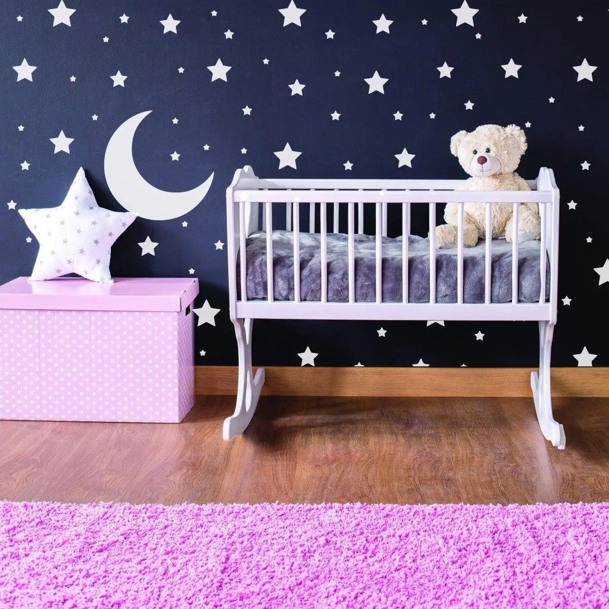 Cozy nursery with white stars wall decals, pink storage box, and a rocking crib for a magical feel.