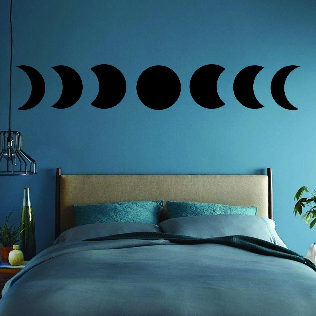 Moon phase wall decor stickers in black above a stylish bed for celestial-themed home decor.