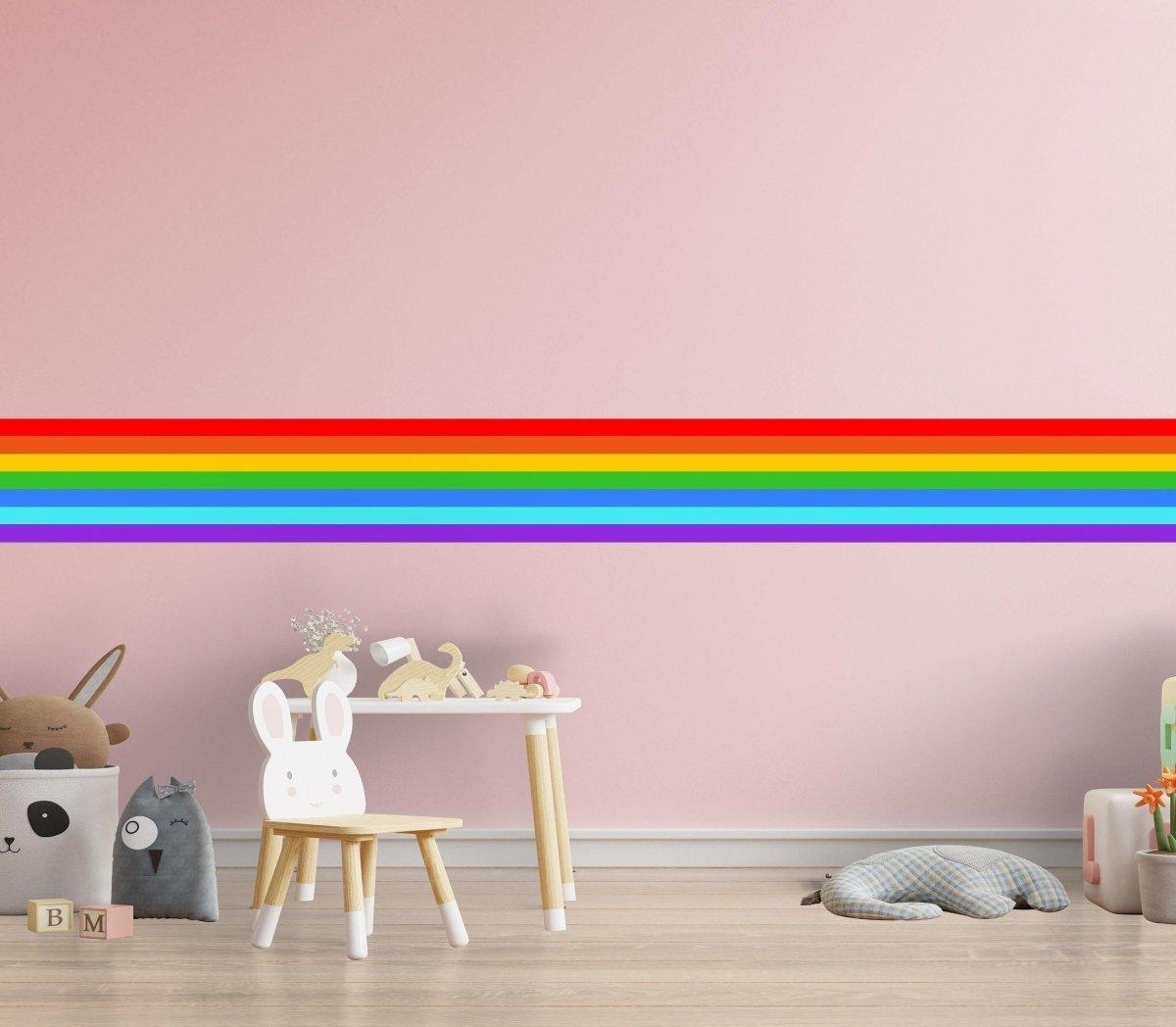 Vibrant rainbow stripe wall decal on pink wall, brightening up a playful nursery setup.