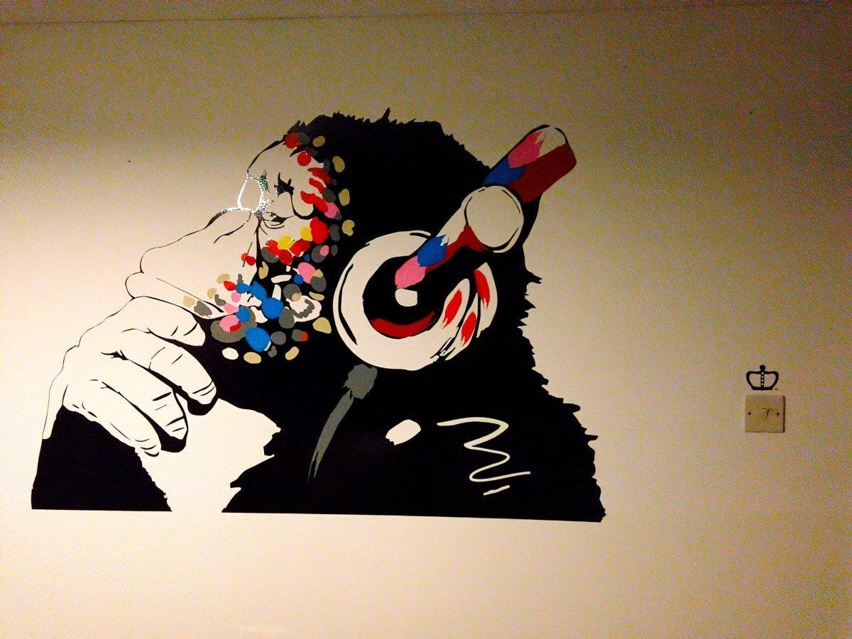 Cool contemplative monkey wall decal with headphones, perfect for kids room decoration inspired by Banksy.