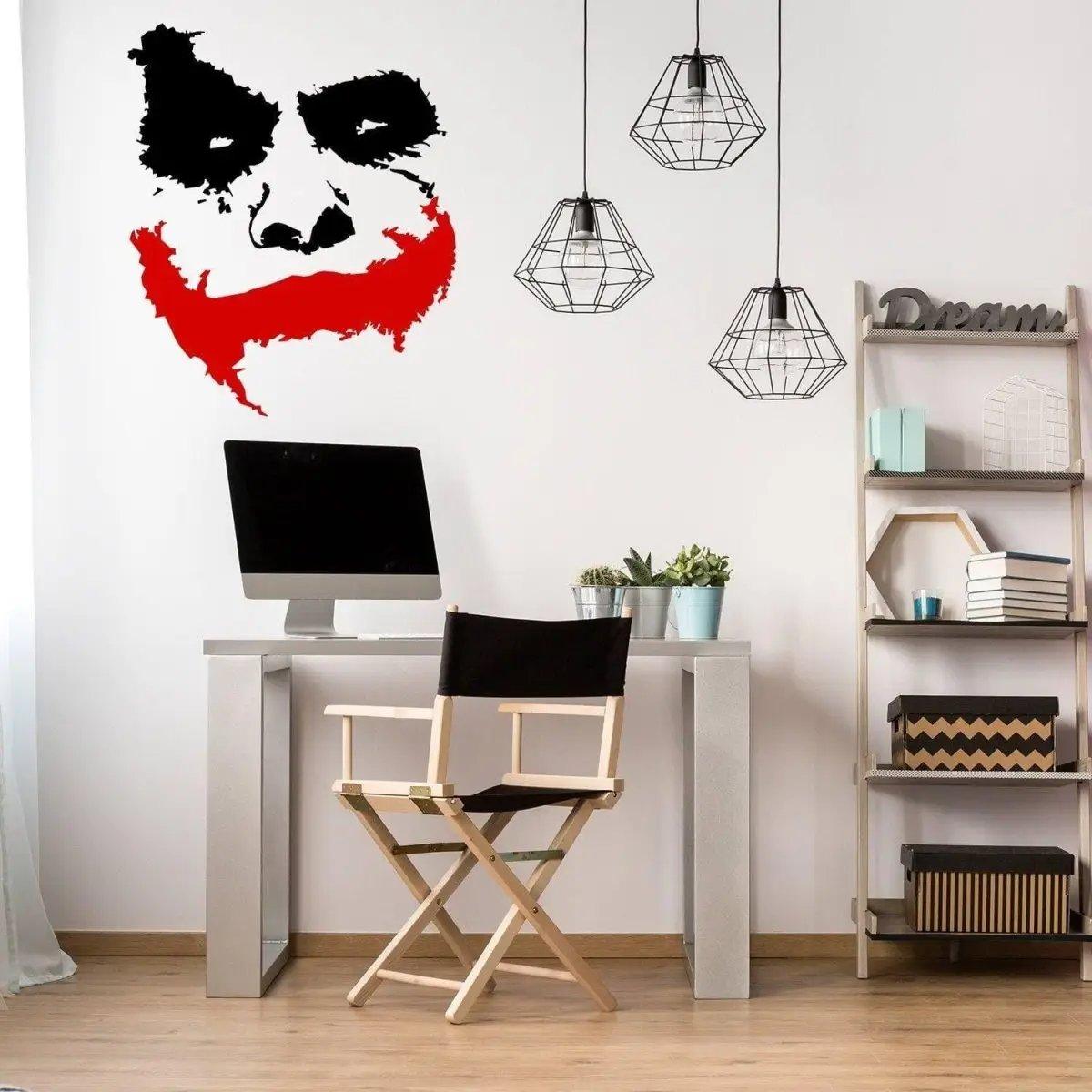 Joker Grin Decal on wall in modern workspace with desk and hanging lights, adding a creepy clown theme.