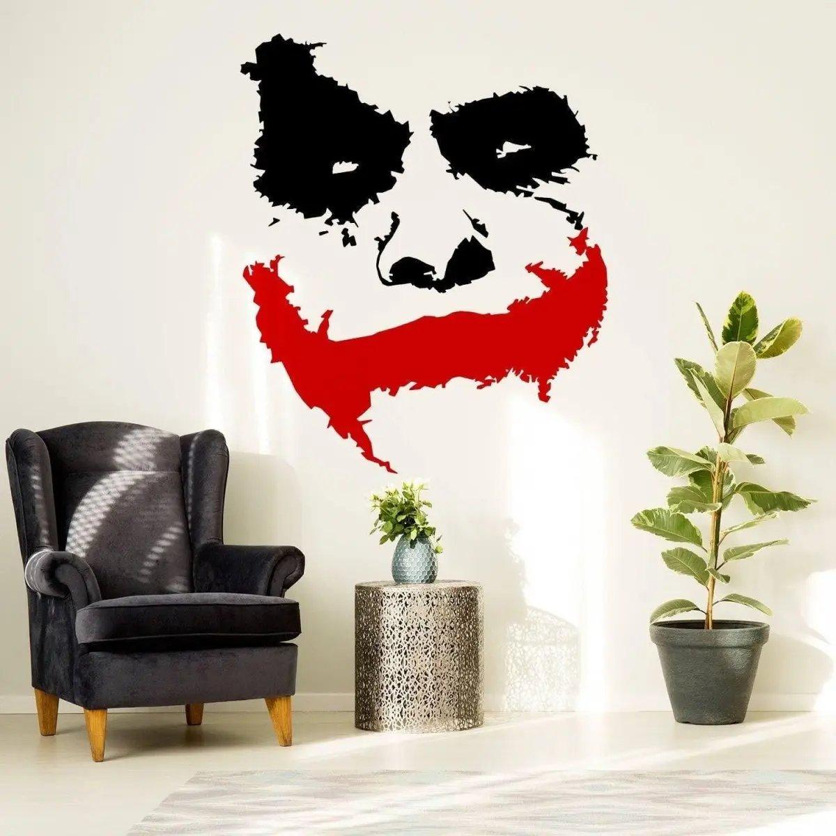 Joker Grin Vinyl Wall Sticker featuring a creepy clown face design on a wall above a stylish chair and plant.