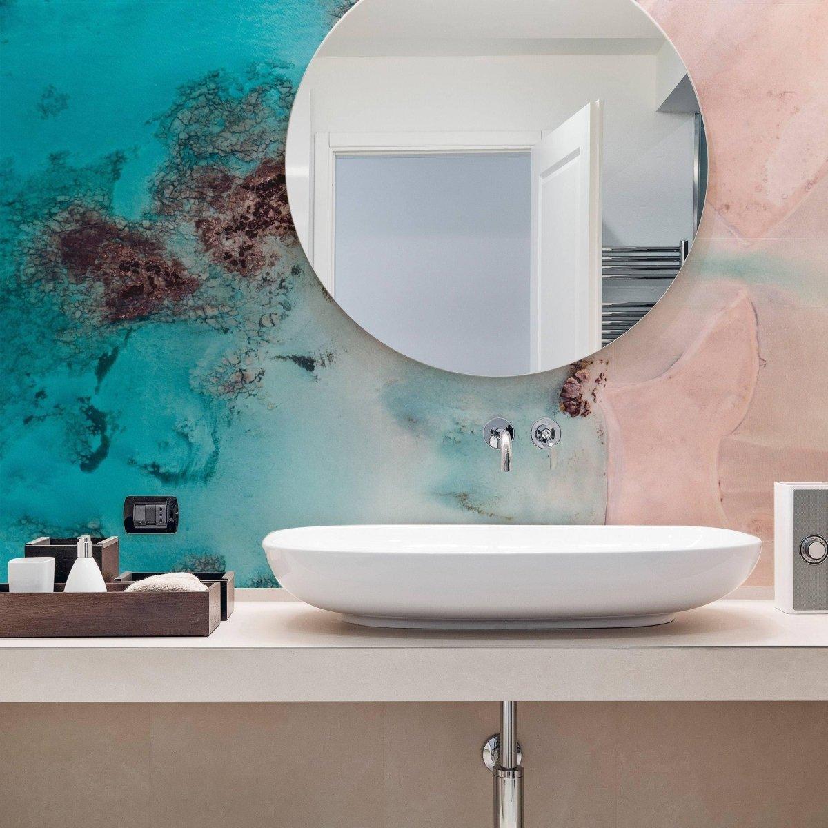 Modern bathroom featuring round mirror and luxurious marble wall covering in teal and peach tones.