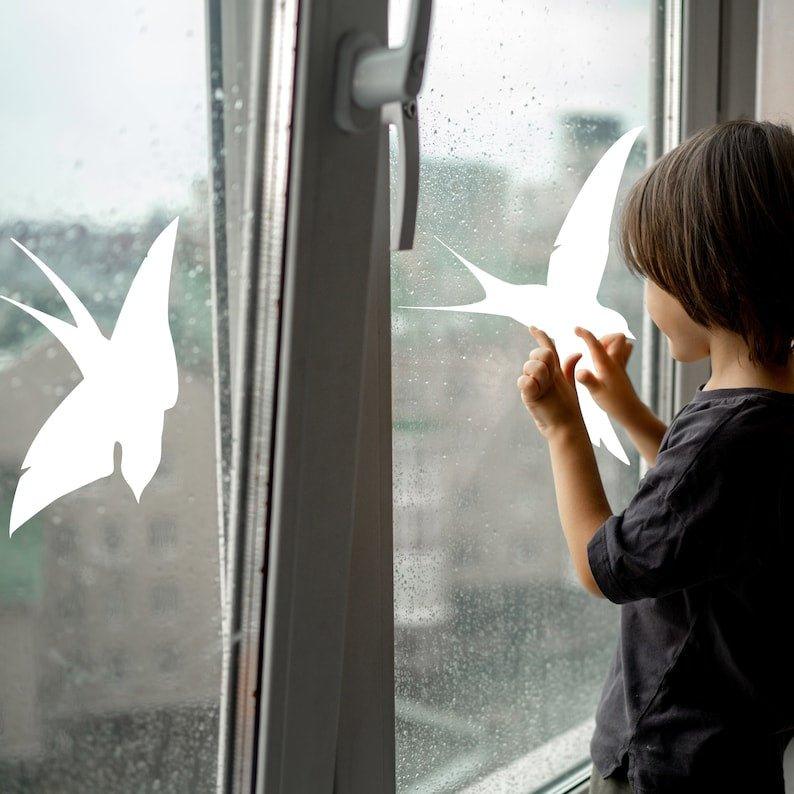 Child applying FeatherGuard bird protection decals on a rainy window to ensure bird safety.