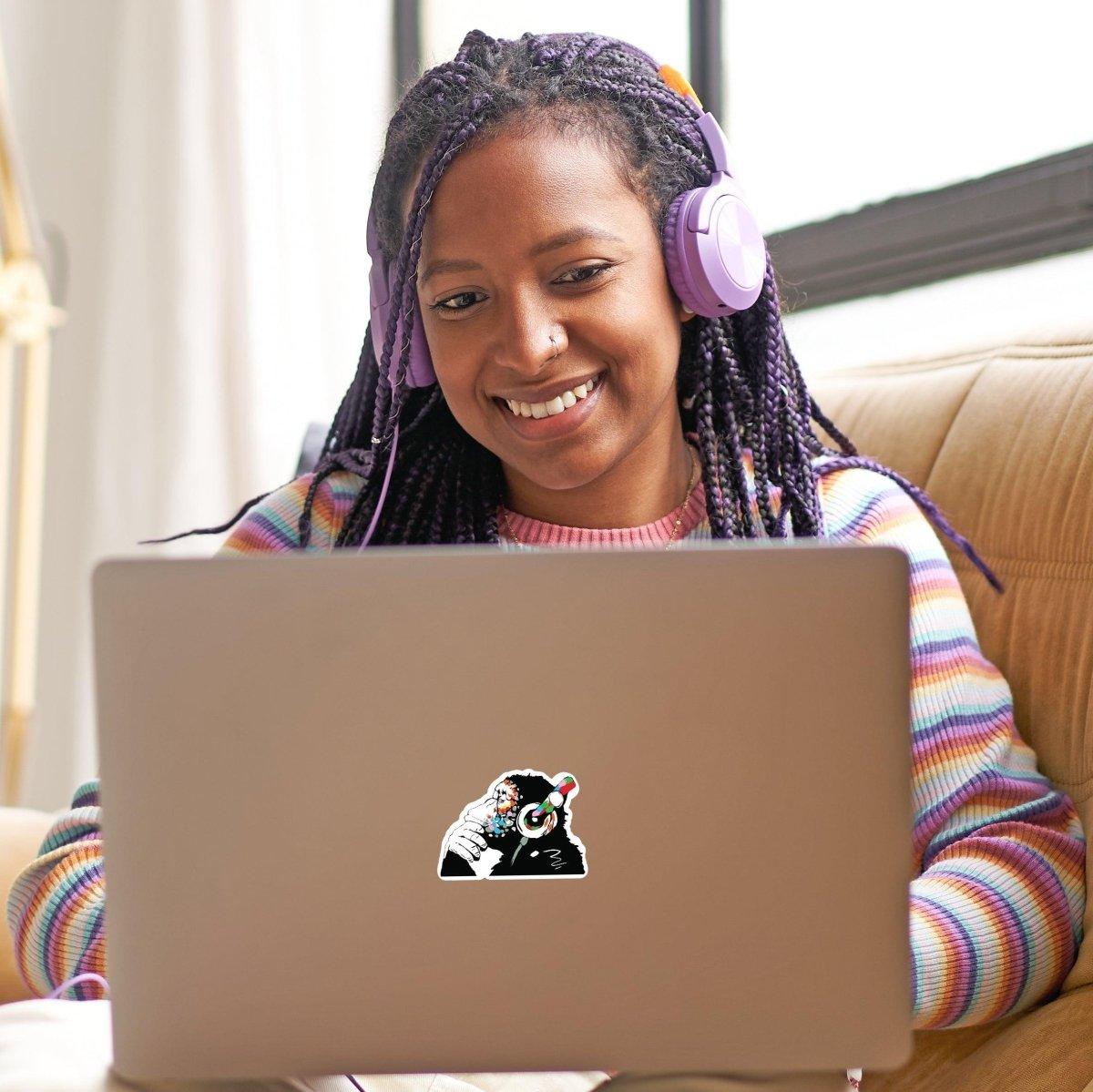Happy girl with braided hair using a laptop with a glowing monkey vinyl decal sticker.