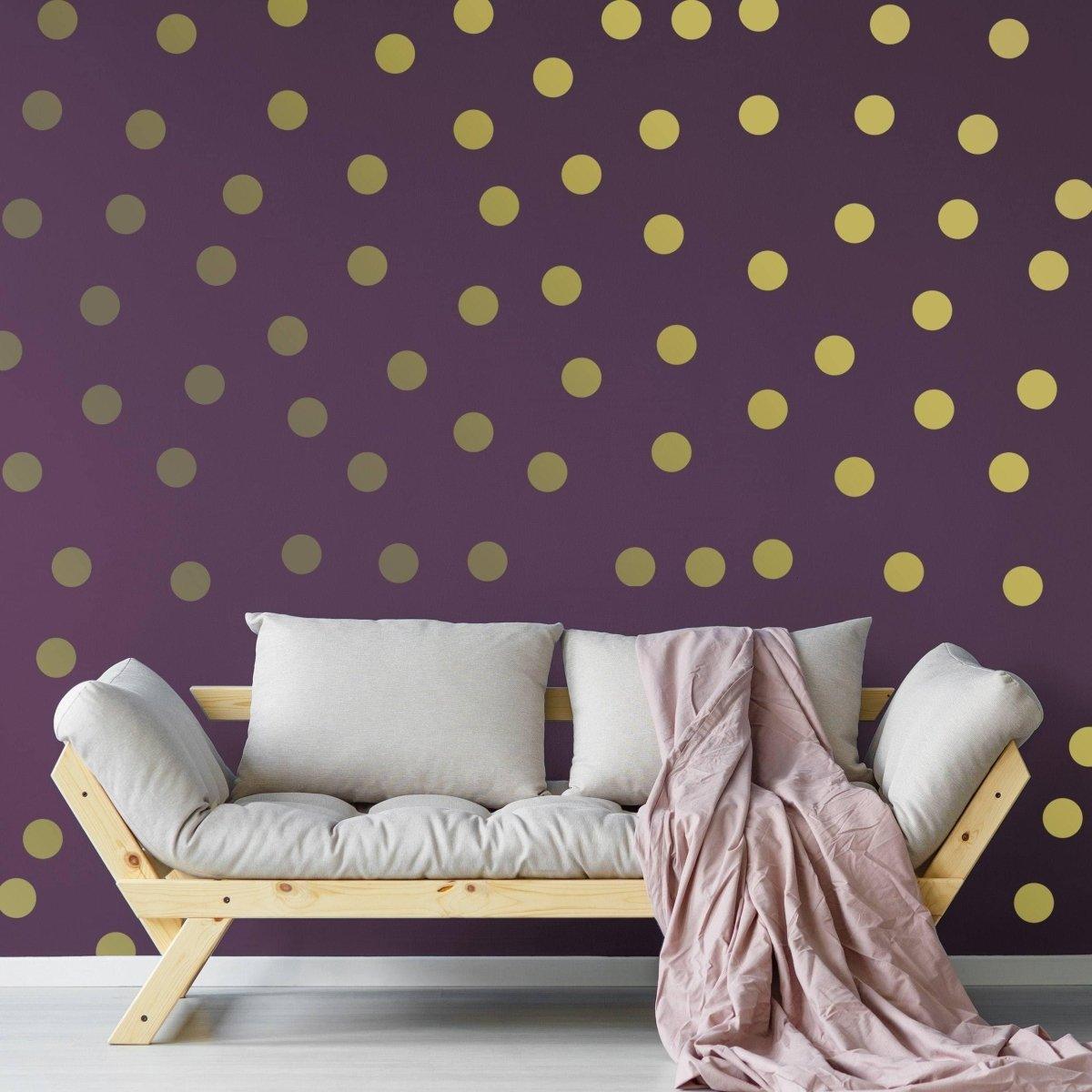 Elegant gold circle wall decals on a purple wall behind a cream sofa with a pink throw blanket.
