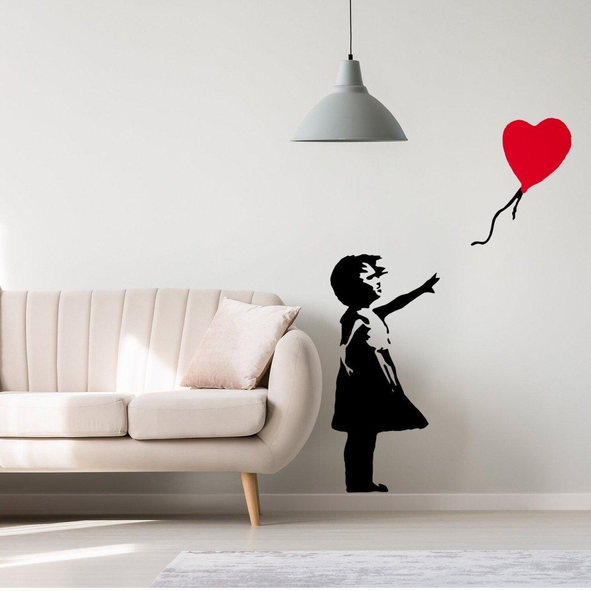Banksy-inspired girl wall decal with heart-shaped balloon on a wall above a couch, adding artistic flair to living space.