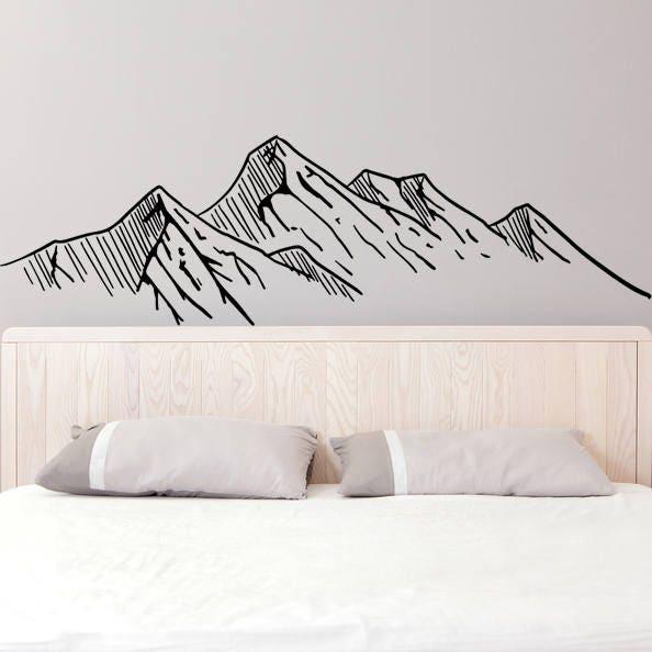 Mountain silhouette wall decal above a bed, adding a touch of nature and adventure to home decor.
