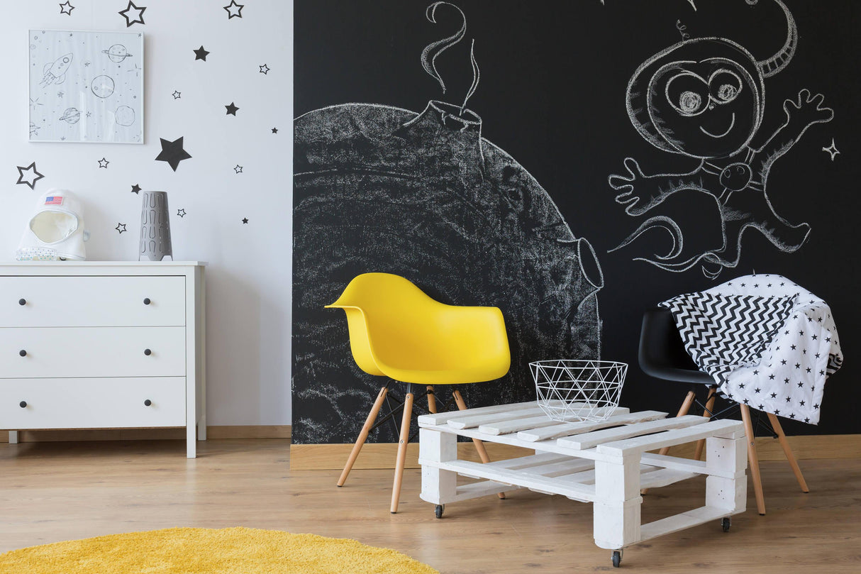 Stylish kids' room with black chalkboard wall art, yellow chair, and white pallet coffee table.