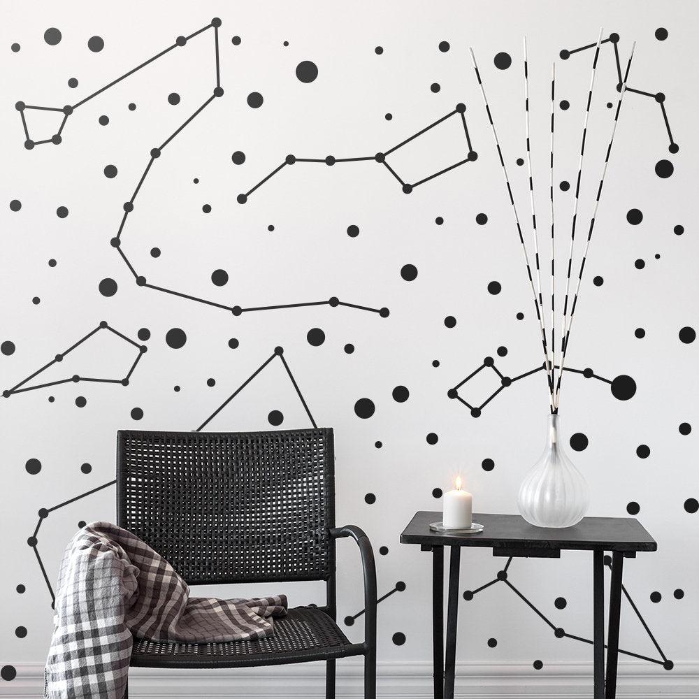Constellations vinyl wall stickers with zodiac designs on a modern wall, featuring a black chair and decor.