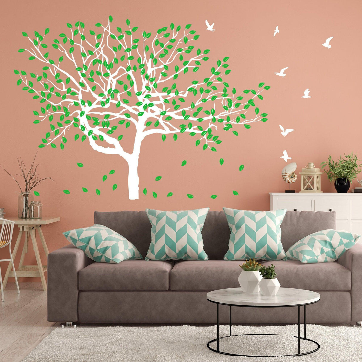 Tree sticker decal with green leaves on a coral wall above a couch with patterned cushions in a cozy living room.