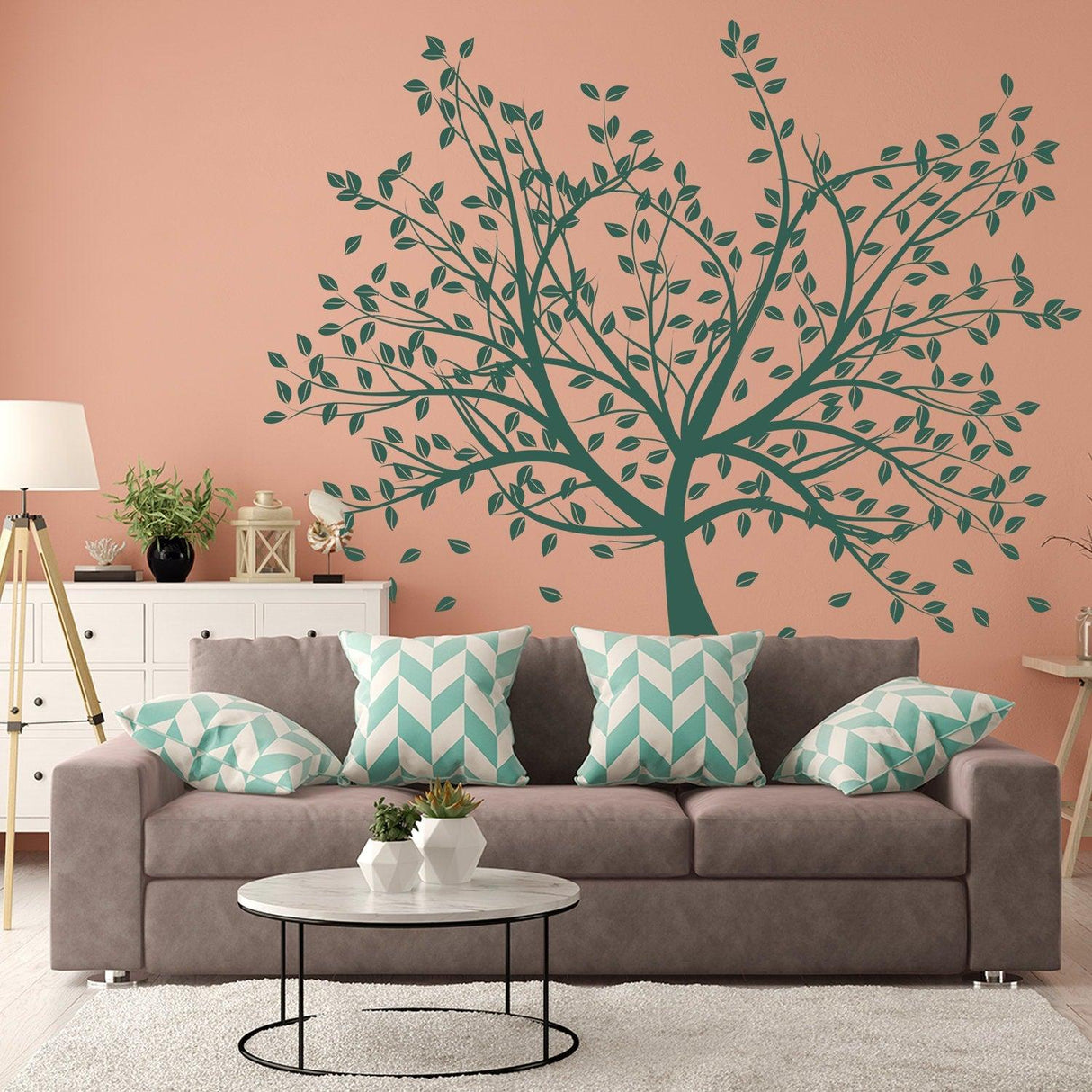 Tree wall decal on pink backdrop above a modern couch with decorative pillows, creating a serene living space.
