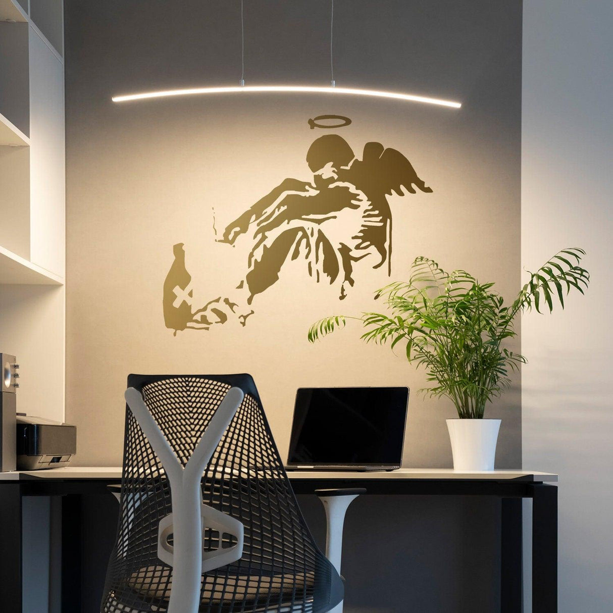 Banksy Fallen Angel wall sticker in a stylish office setting with a modern desk and plants.