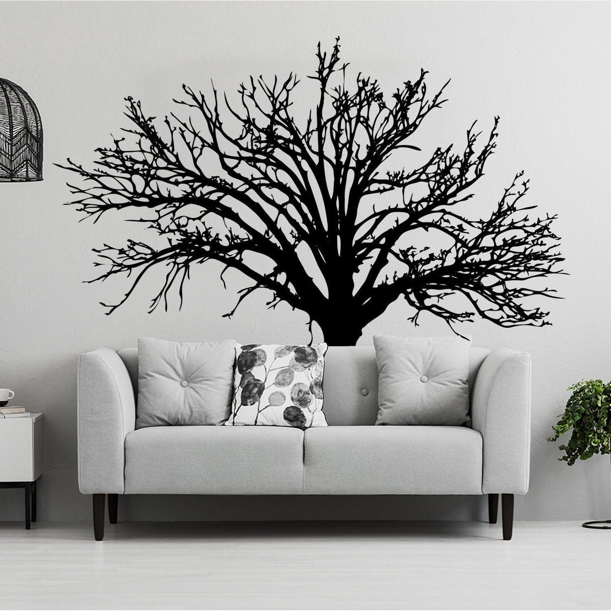 Stylish wall decal of a black tree design above a modern gray couch, enhancing home decor.