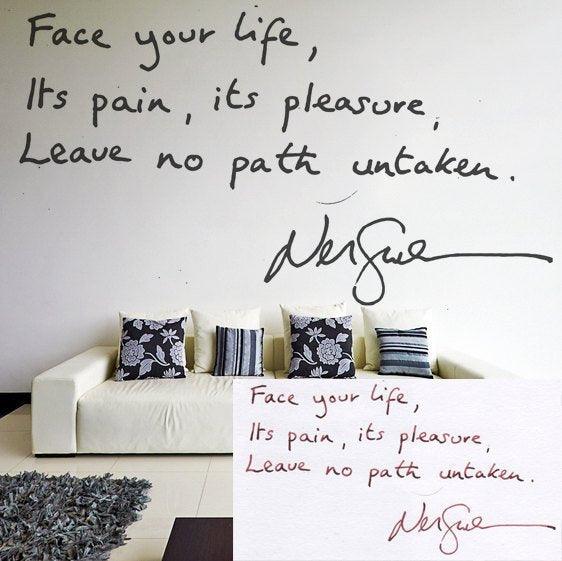 Wall decal of a handwritten quote: 'Face your life, Its pain, its pleasure, Leave no path untaken' above a sofa.