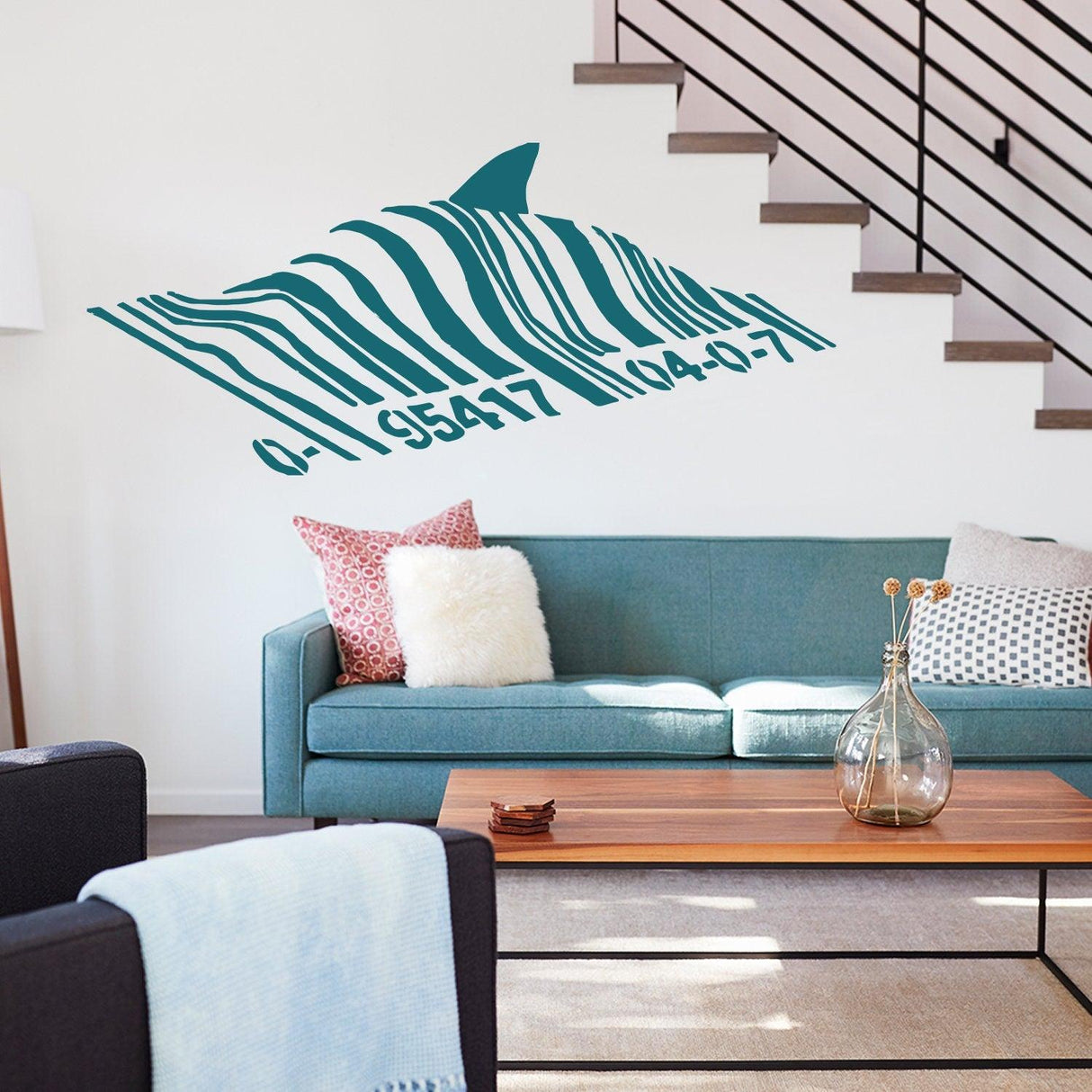 Banksy Barcode Shark Wall Sticker vinyl decal above a cozy teal sofa in a stylish living room decor.